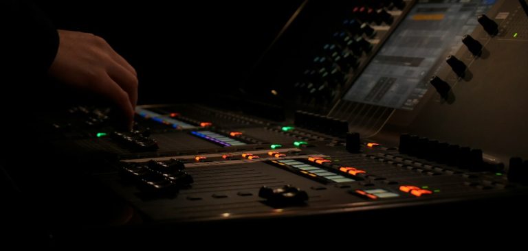 Educational technology installation Close-up of a hand adjusting controls on a sound mixing console in low light.