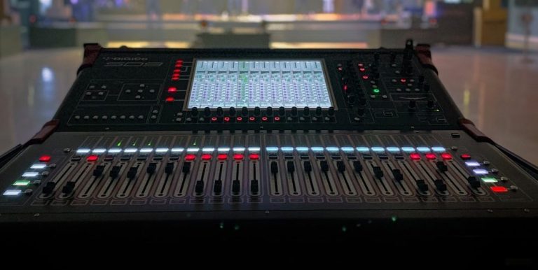 Digital audio mixer with various controls and illuminated buttons.